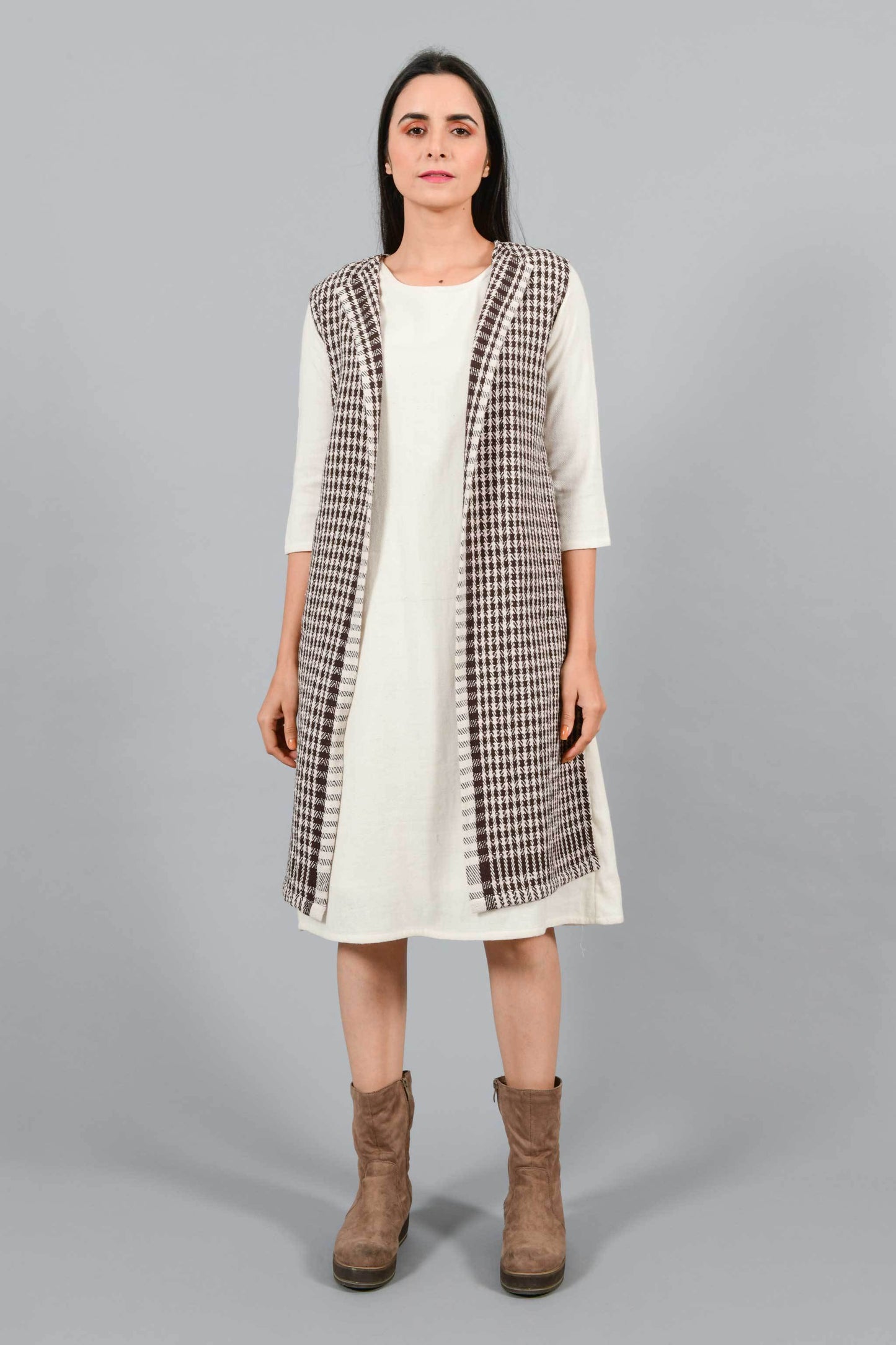 Front pose of an Indian Womenswear female model wearing Kora Brown handspun and handwoven khadi long Jacket over an off-white cashmere cotton dress by Cotton Rack.