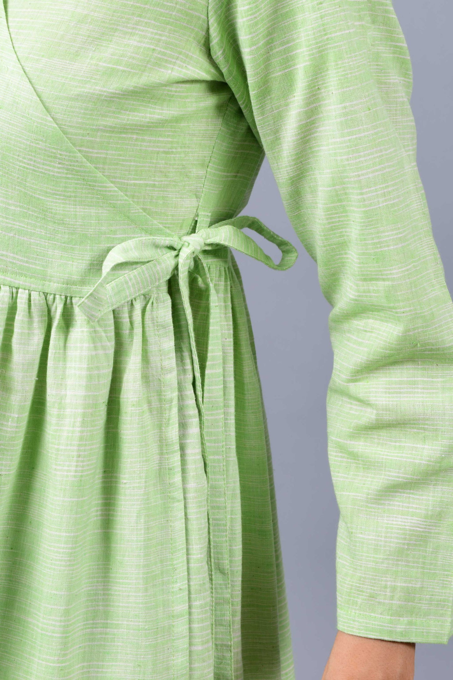 close up of a model wearing an angrakha dress kurta in green and white space dyed fine handspun handwoven khadi cotton from west bengal