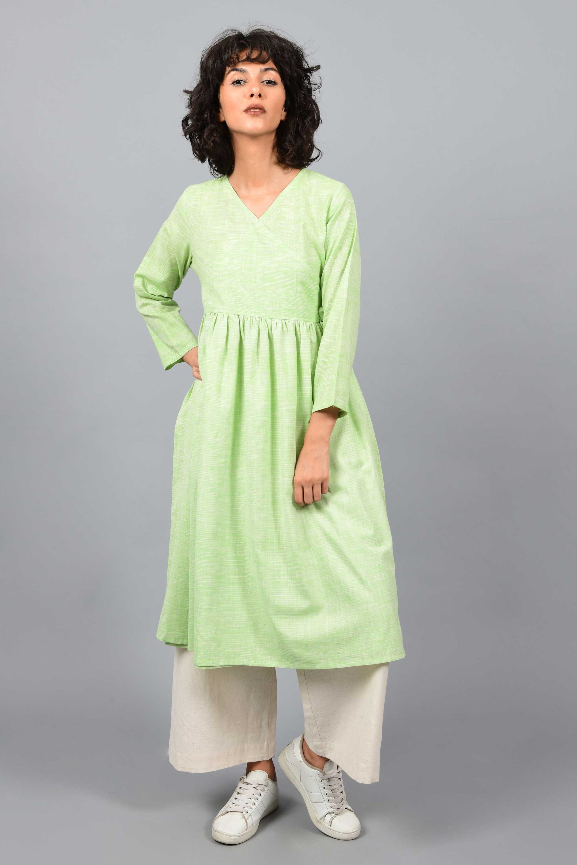 front of a model wearing an angrakha dress kurta in green and white space dyed fine handspun handwoven khadi cotton from west bengal with off white pants
