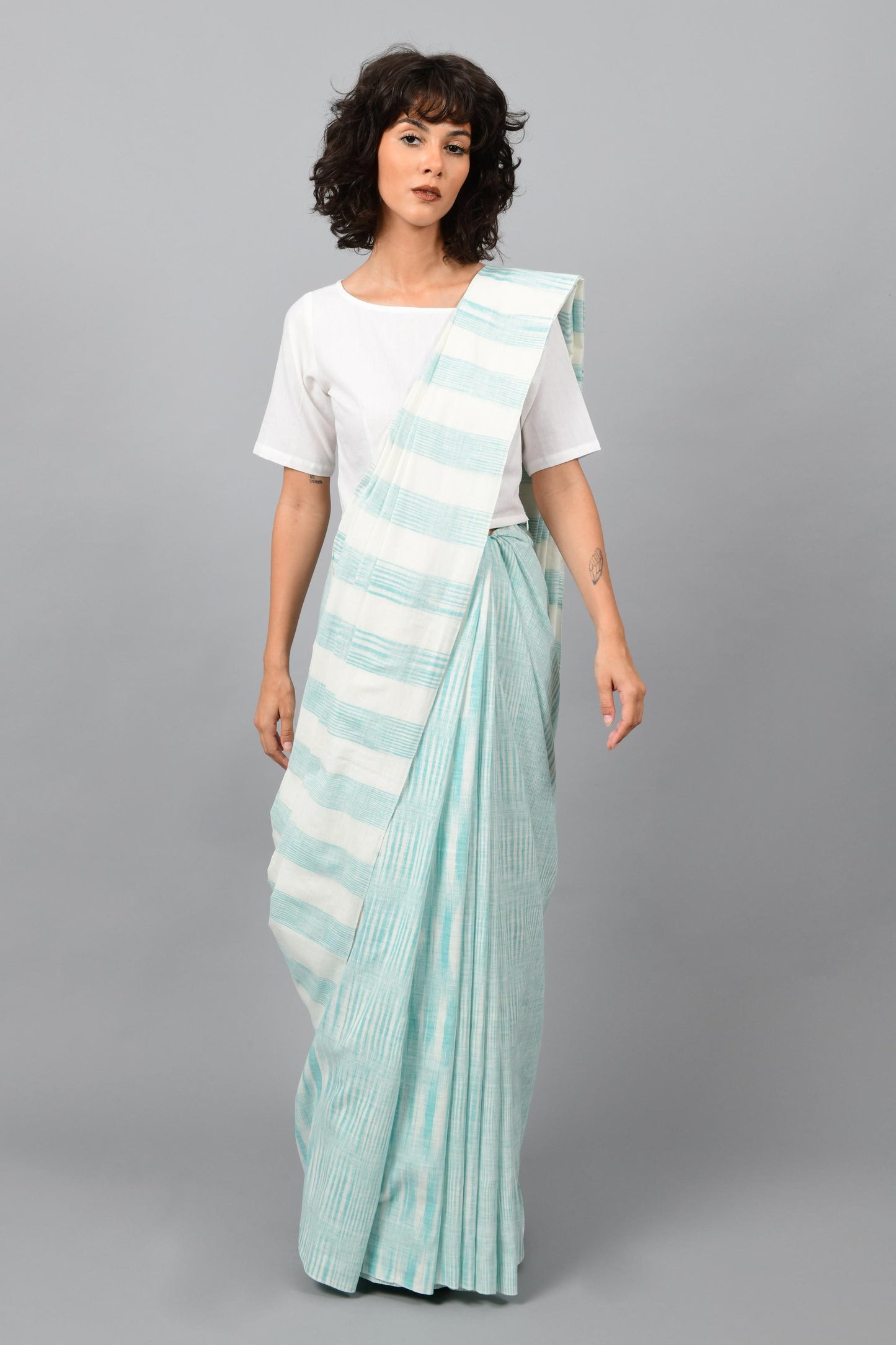 Front pose of a female womenswear fashion model draped in a aquamarine blue & white space dyed homespun and handwoven cotton sari by Cotton Rack.