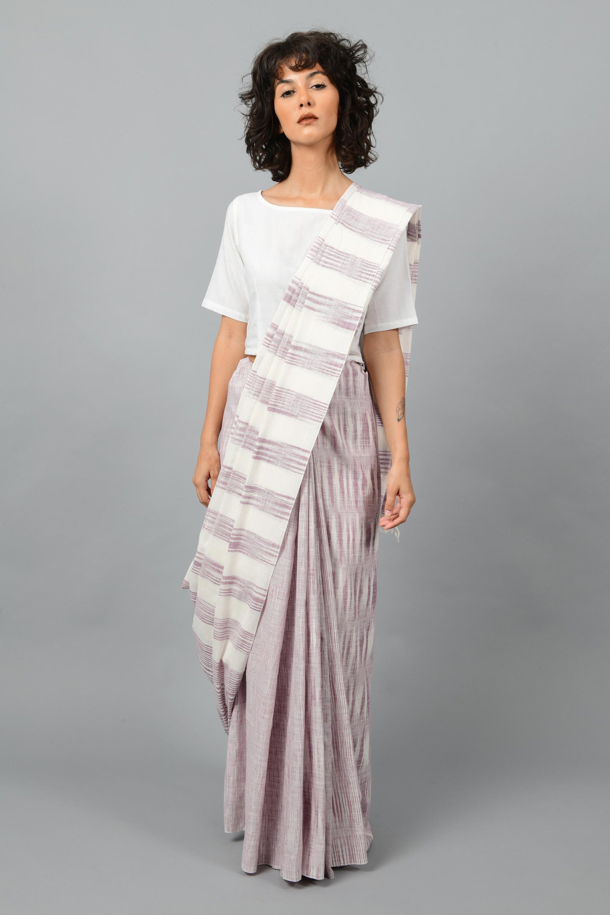 Front pose of a female womenswear fashion model draped in a purple & white space dyed homespun and handwoven cotton saree by Cotton Rack.