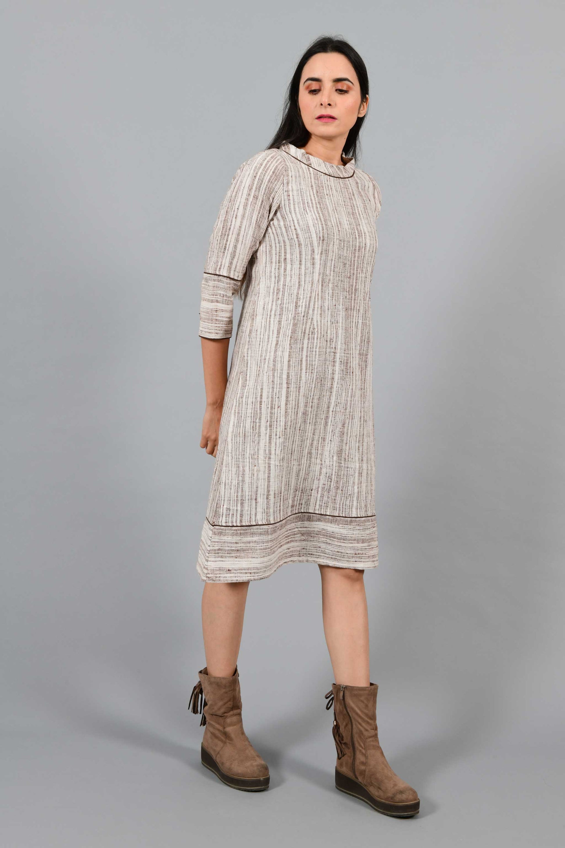 Side walking pose of an Indian Womenswear female model wearing brown handspun and handwoven cotton a-line dress by Cotton Rack.