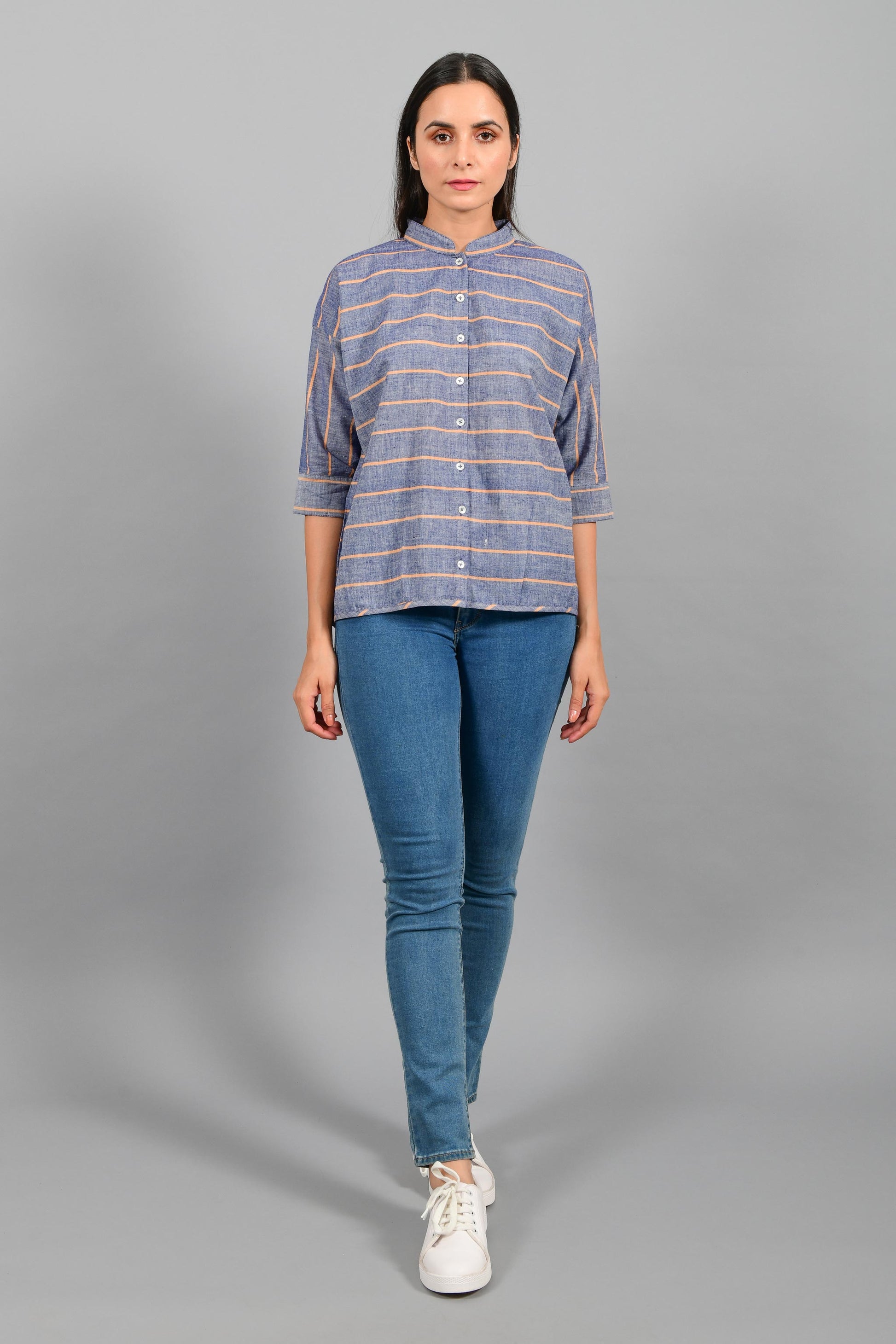 Front pose of an Indian female womenswear fashion model in a blue chambray with orange stripes handspun and handwoven khadi cotton free size top by Cotton Rack.