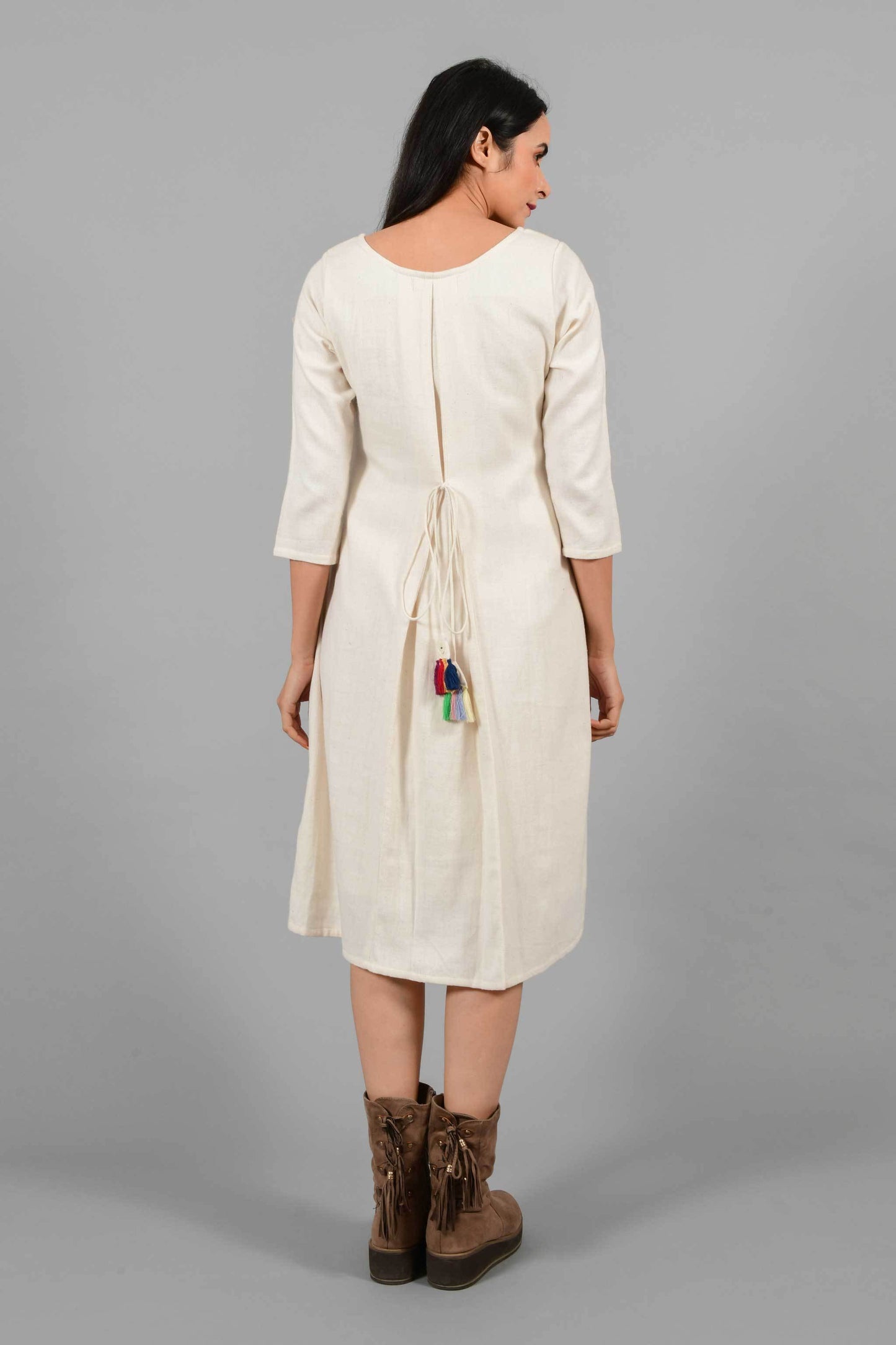 Back pose of an Indian female womenswear fashion model in an off-white Cashmere Cotton A-line Dress with box pleat on the back made using handspun and handwoven khadi cotton by Cotton Rack.