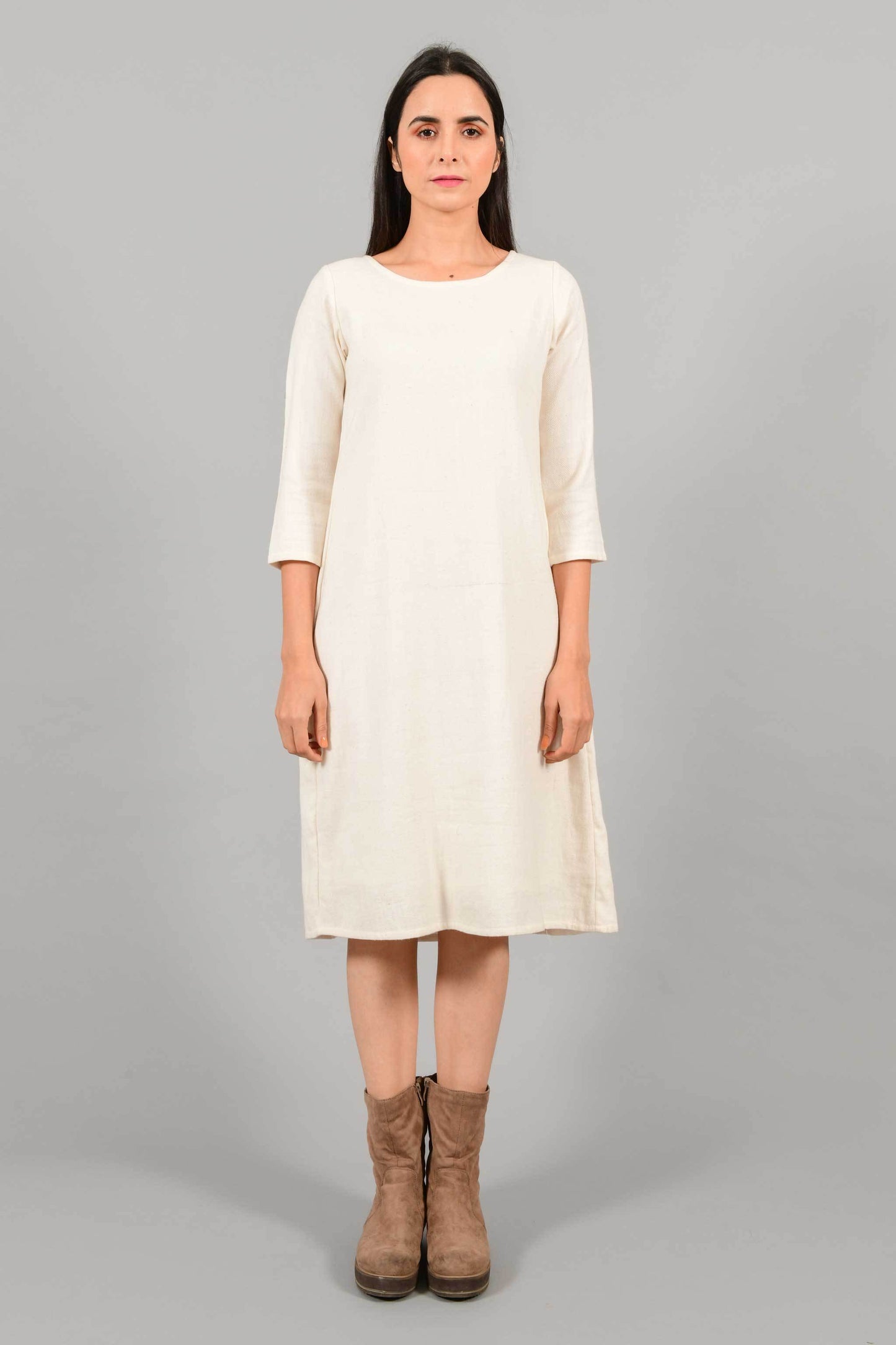 Front pose of an Indian female womenswear fashion model in an off-white Cashmere Cotton A-line Dress with box pleat on the back made using handspun and handwoven khadi cotton by Cotton Rack.