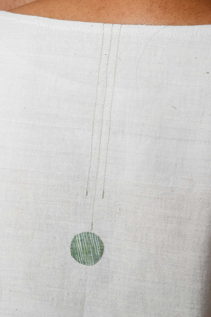 Close up of a circular cotton green fabric patch and stitching details.