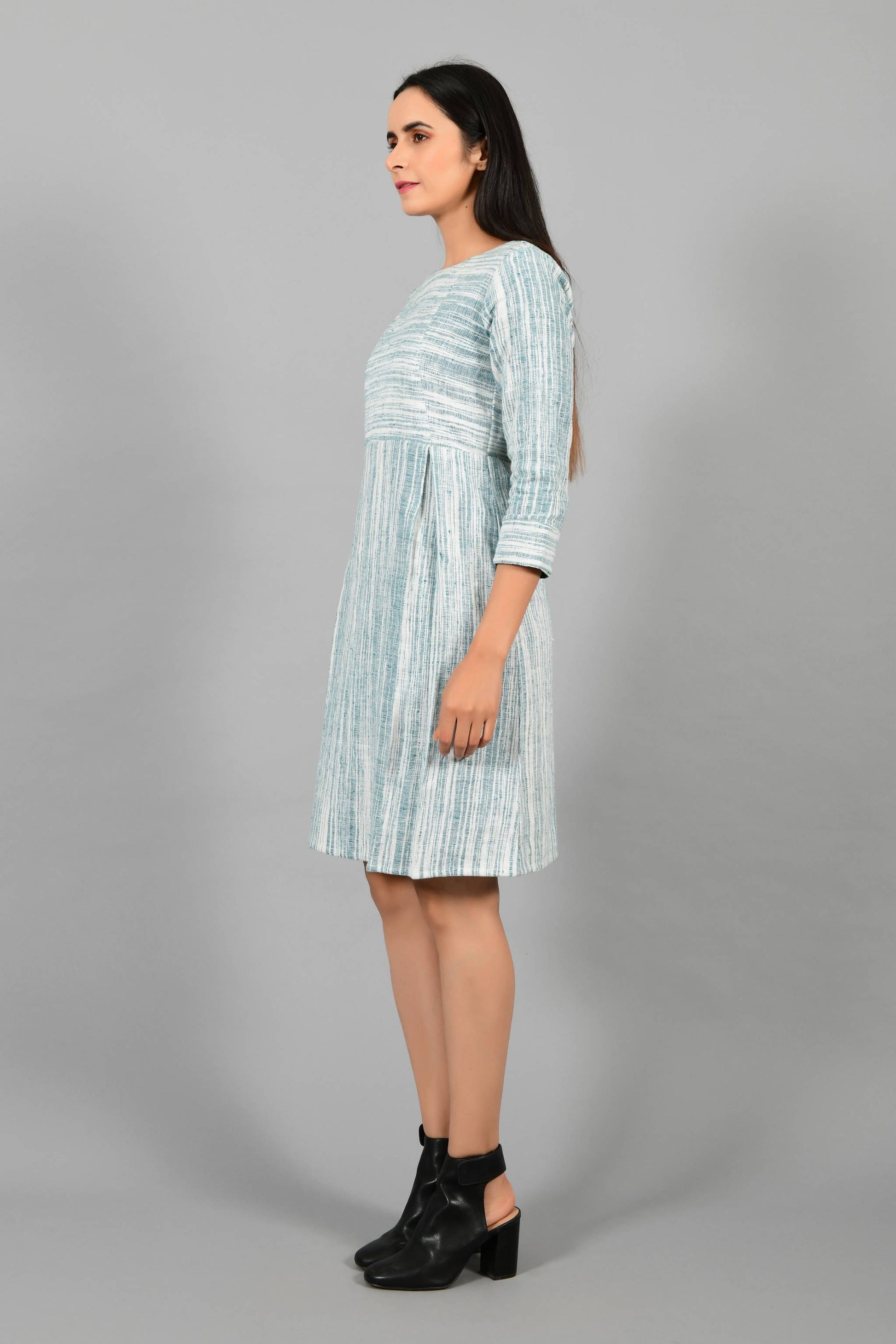 Side pose of an Indian Womenswear female model wearing pine green handspun and handwoven cotton dress by Cotton Rack.