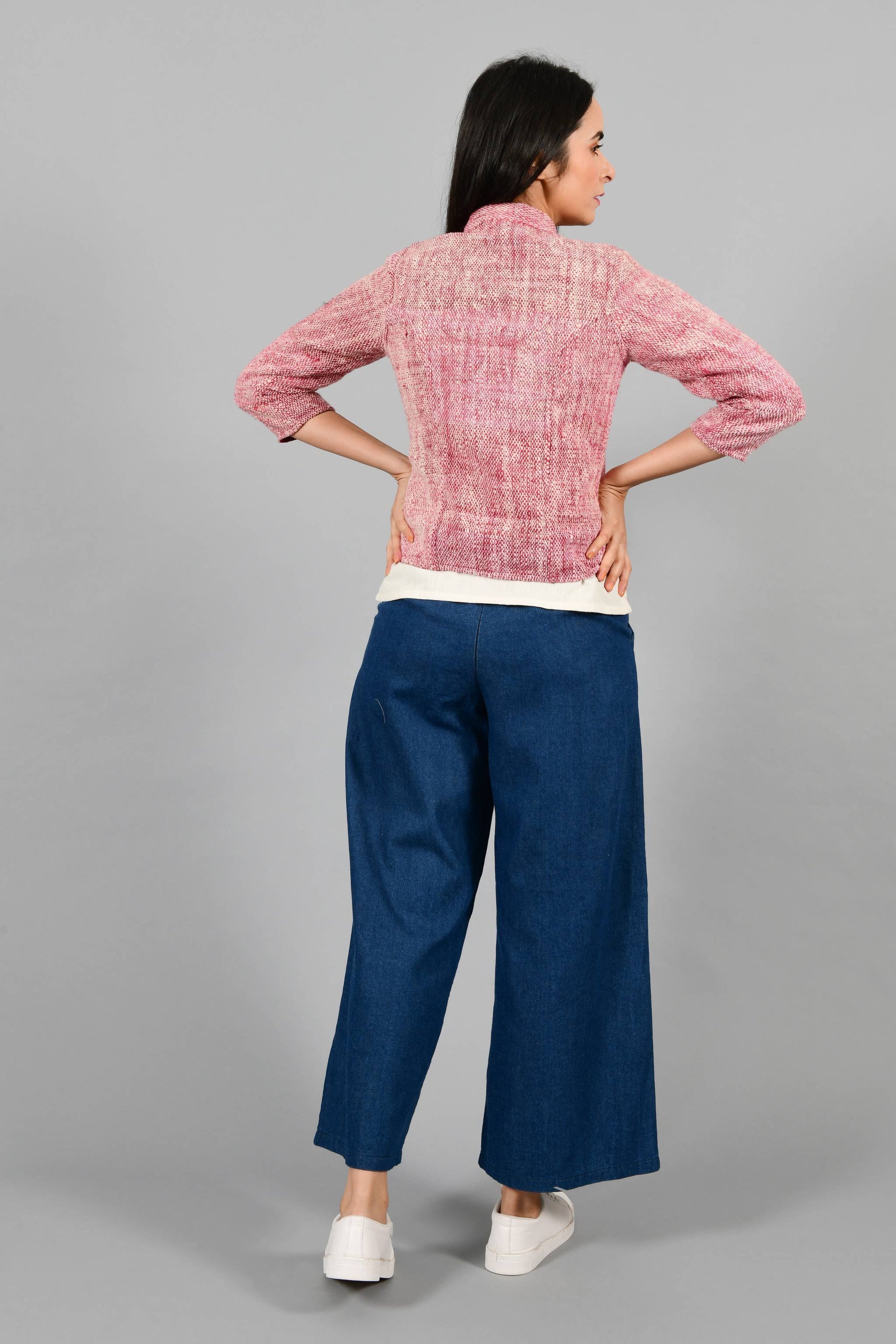 Back pose of an Indian Womenswear female model wearing plum red Gandhi Charkha spun and handwoven khadi buttoned mandarin collar Jacket over an off-white spaghetti and indigo palazzos by Cotton Rack.