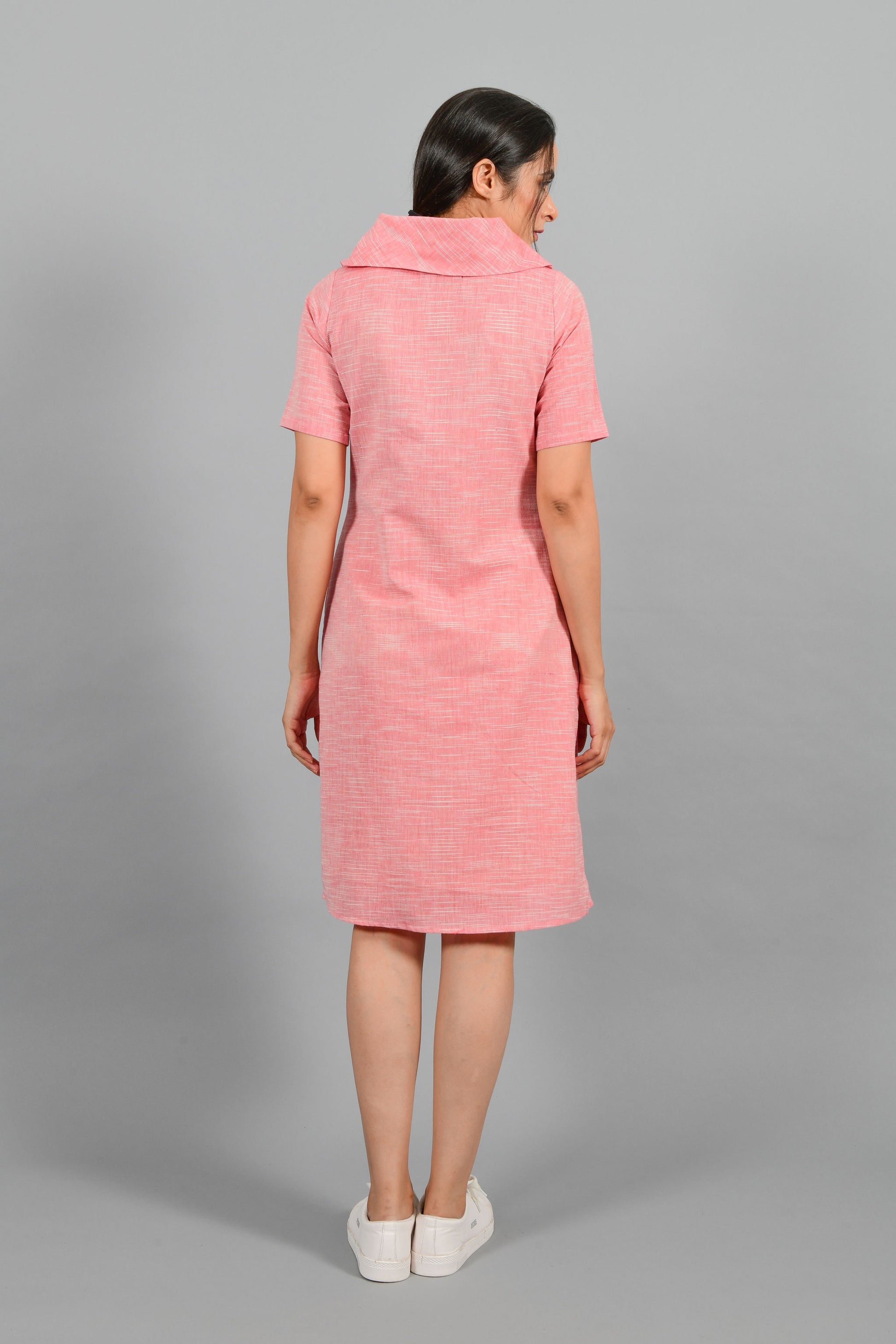 Back pose of an Indian female womenswear fashion model in a Pink and White space dyed cowl neck, elbow sleeve handspun and handwoven khadi cotton dress by Cotton Rack.