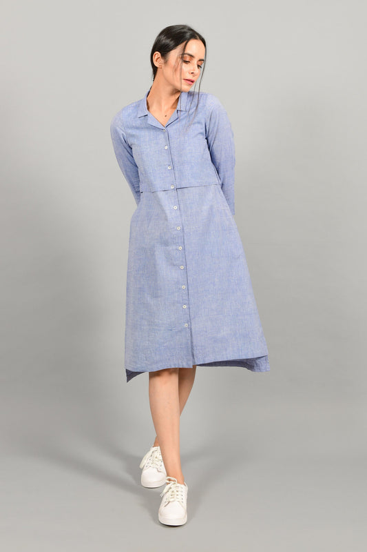 Front stylised pose of an Indian female womenswear fashion model in a blue chambray handspun and handwoven khadi cotton shirt dress by Cotton Rack.