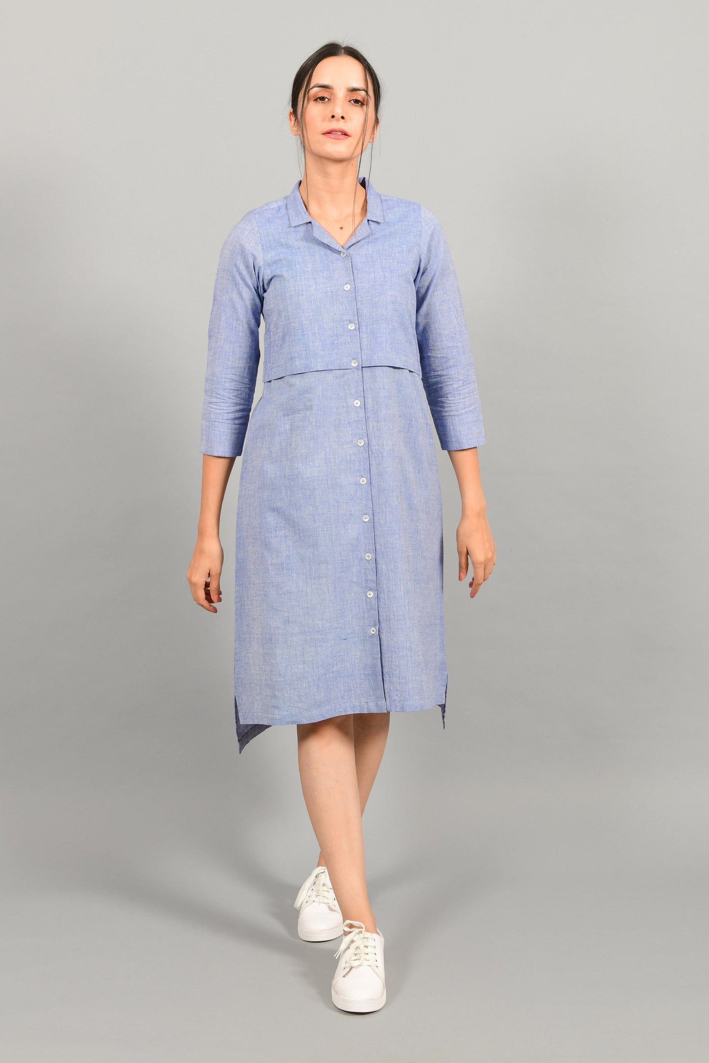 Front pose of an Indian female womenswear fashion model in a blue chambray handspun and handwoven khadi cotton shirt dress by Cotton Rack.