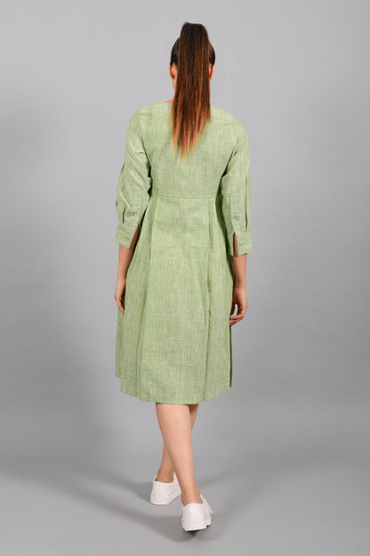 Back pose of an Indian female womenswear fashion model in a space dyed olive green handspun and handwoven khadi cotton pleated dress-kurta by Cotton Rack.