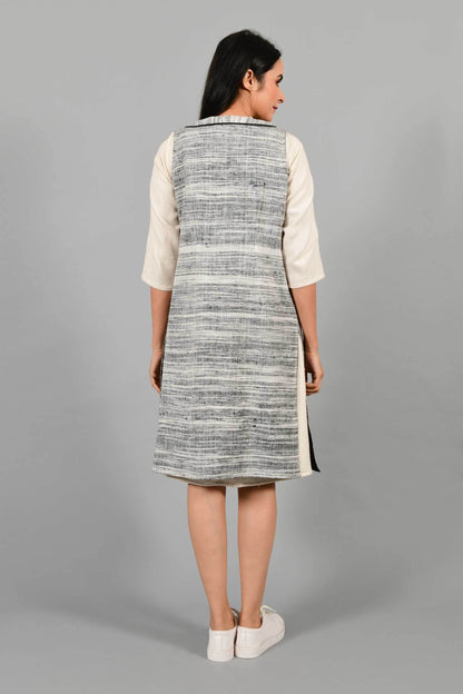 Back pose of an Indian Womenswear female model wearing black and white thicker handspun and handwoven khadi Jacket over a Cashemer Cotton Dress by Cotton Rack.
