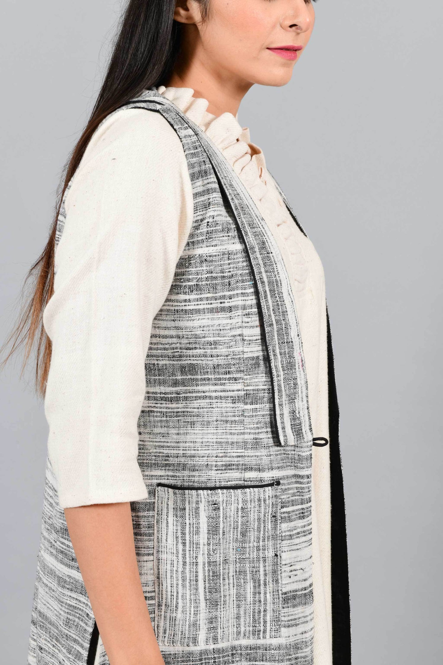 Side close up of an Indian Womenswear female model wearing black and white thicker handspun and handwoven khadi Jacket over a Cashemer Cotton Dress by Cotton Rack.