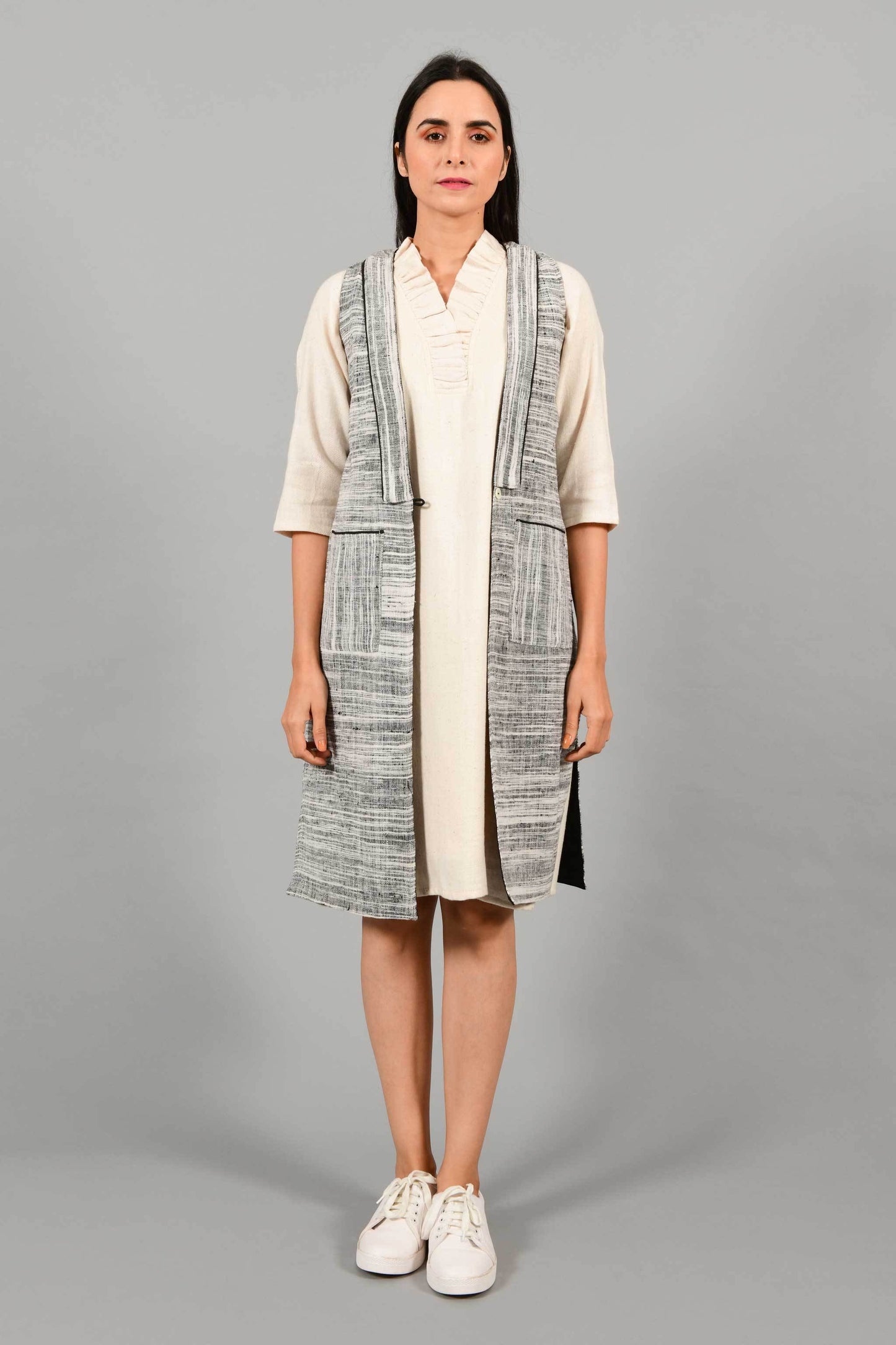 Front pose of an Indian Womenswear female model wearing black and white thicker handspun and handwoven khadi Jacket over a Cashemer Cotton Dress by Cotton Rack.