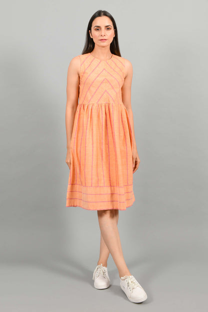 Front pose of an Indian female womenswear fashion model in a orange chambray handspun and handwoven khadi cotton with red stripes by Cotton Rack. The dress has gathers at waist. and the stripes are arranged in attractive manner.