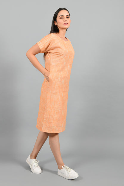 Stylised side pose of an Indian female womenswear fashion model in an orange space dyed handspun and handwoven khadi cotton panelled dress by Cotton Rack.