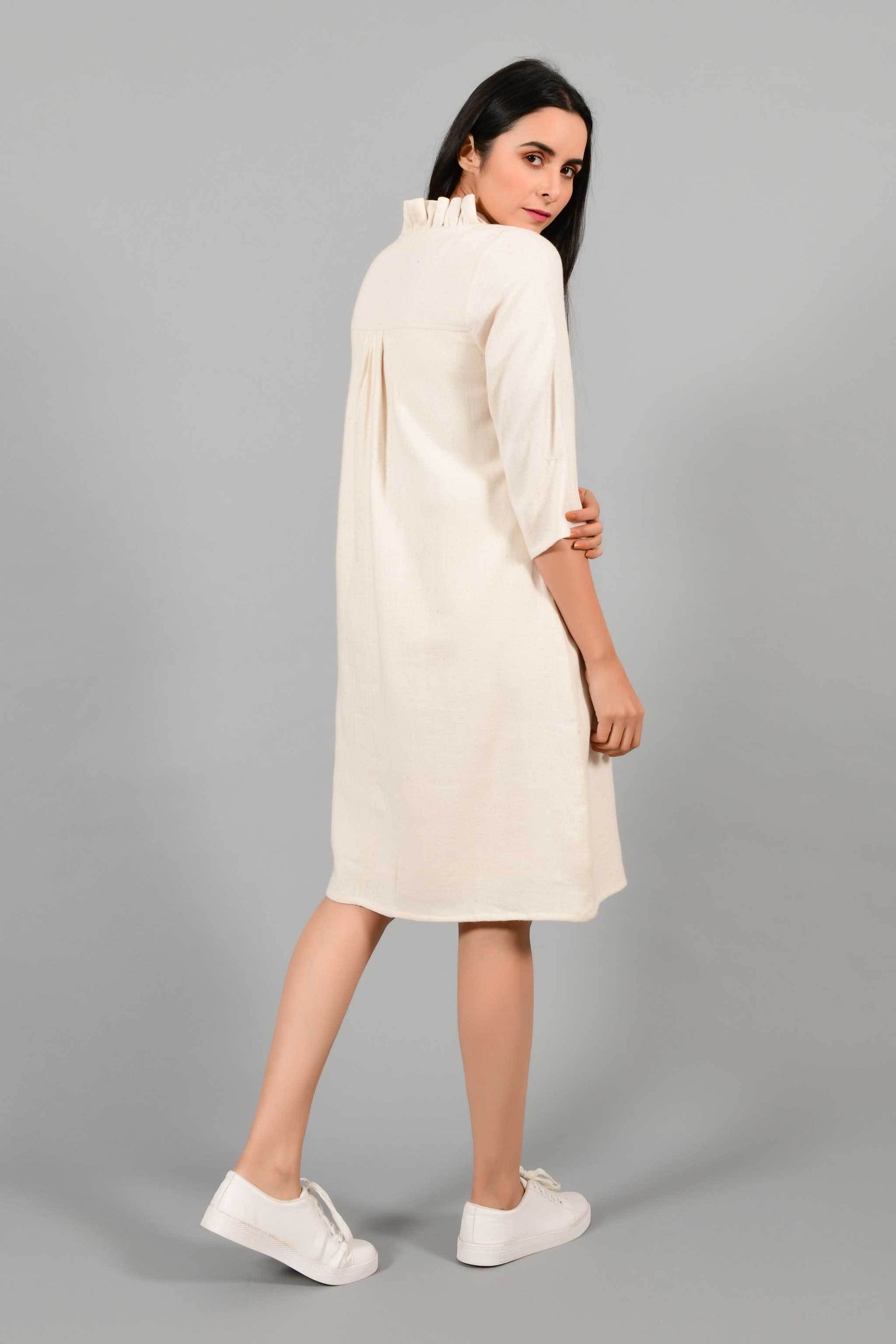 Back pose of an Indian female womenswear fashion model in an off-white Cashmere Cotton Dress with flared neck, made using handspun and handwoven khadi cotton by Cotton Rack.