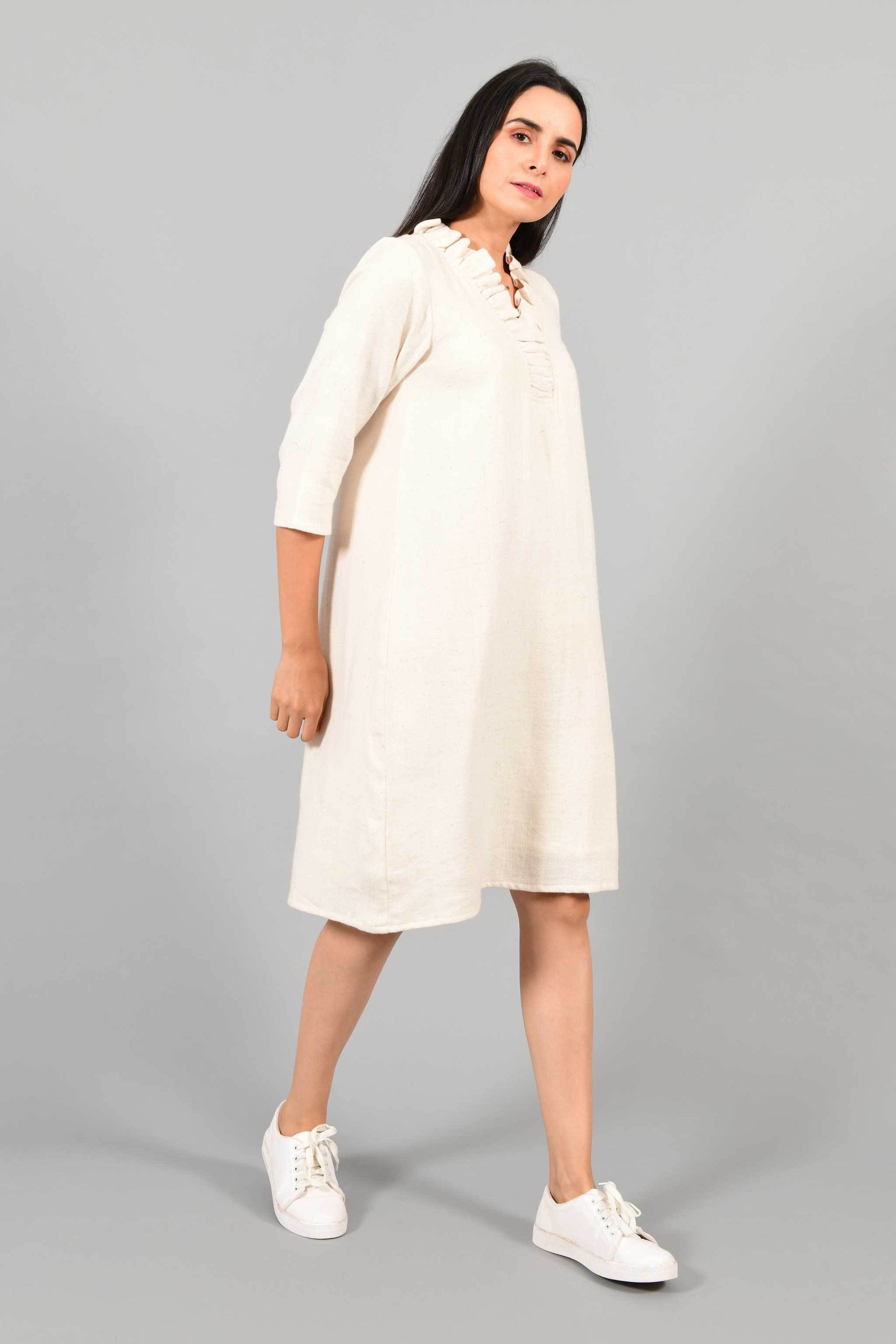 Side pose of an Indian female womenswear fashion model in an off-white Cashmere Cotton Dress with flared neck, made using handspun and handwoven khadi cotton by Cotton Rack.