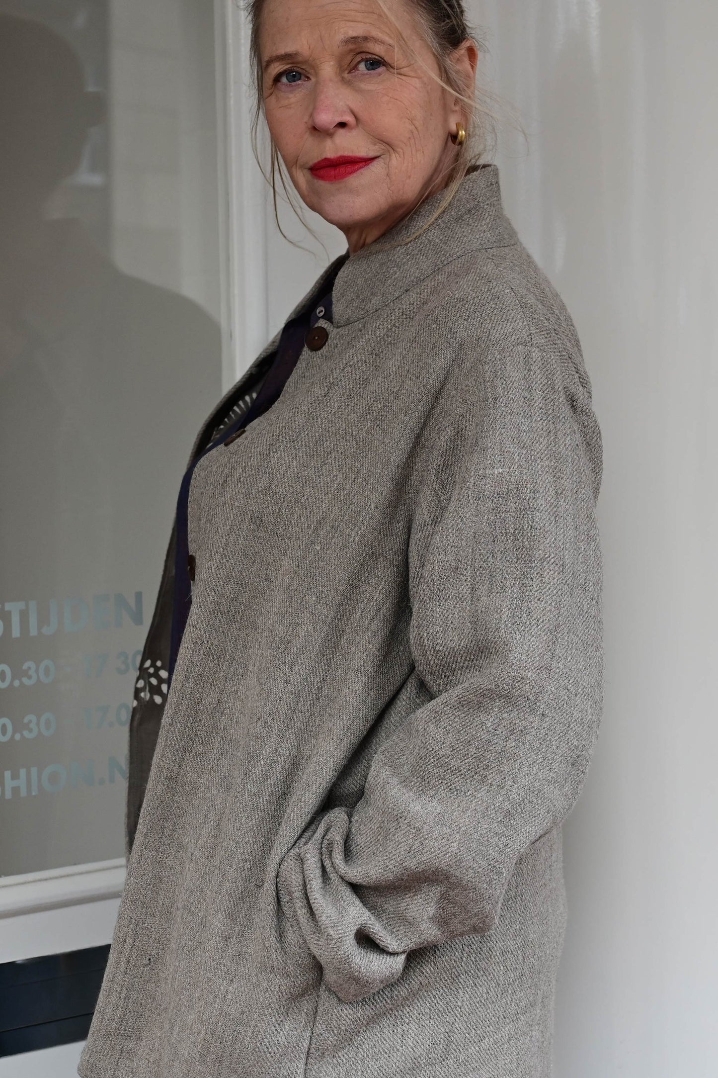 A middle aged european model posing wearing brown woolen jacket with brown hand block printed chanderi silk cotton jacket lining with buttons open. Jacket is made of handspun and handwoven Indian sheep wool by Cotton Rack.