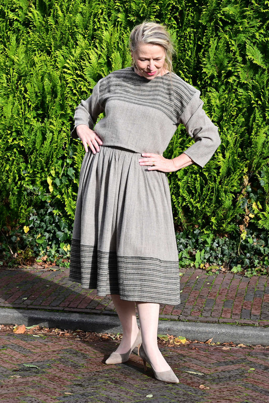 Standing front pose of a middle aged female model on a european street wearing a woolen crop top and gathered skirt set handmade by Cotton Rack.